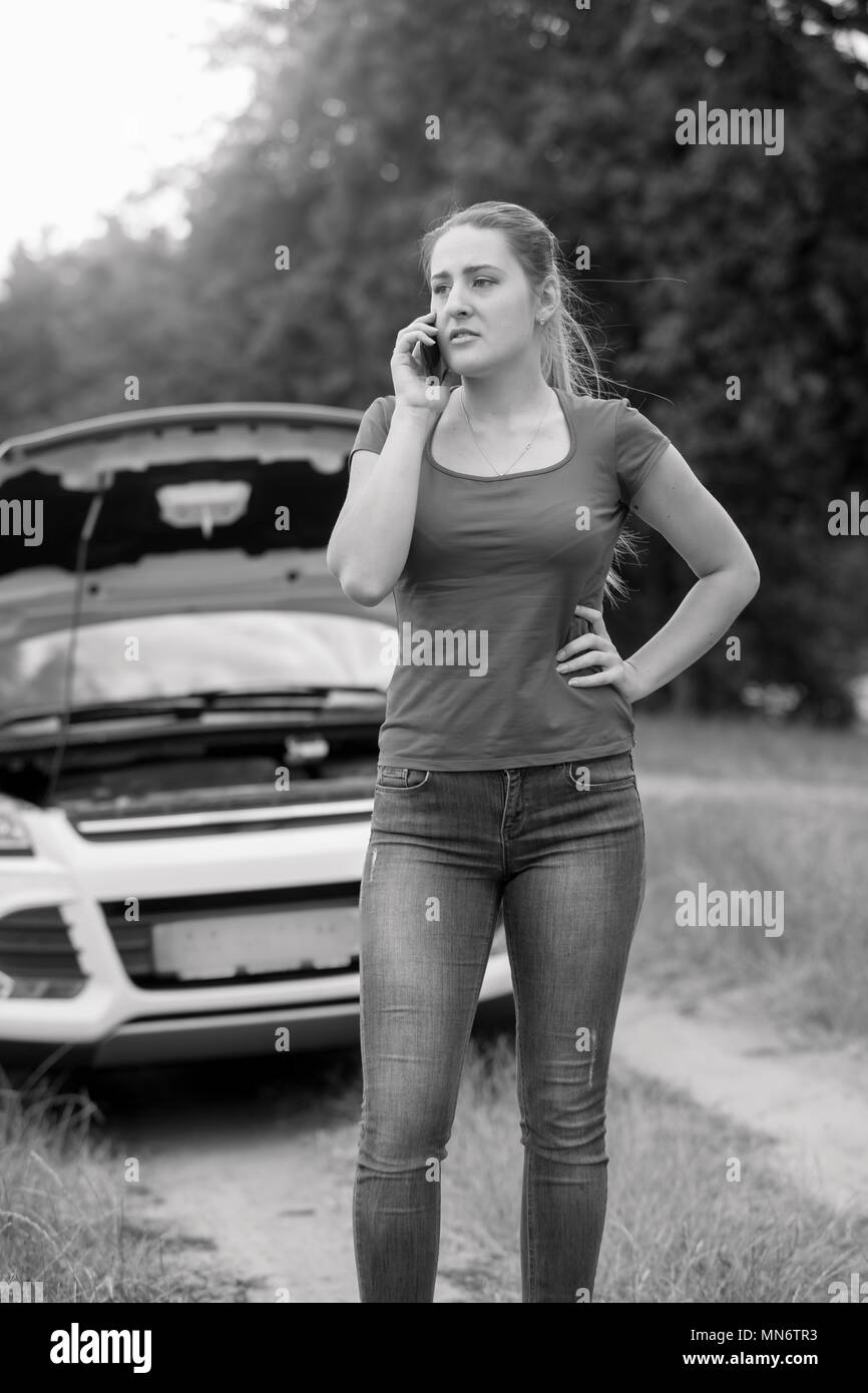 Image en noir et blanc de jeunes femme appelant l'assistance automobile dans le domaine de service Banque D'Images