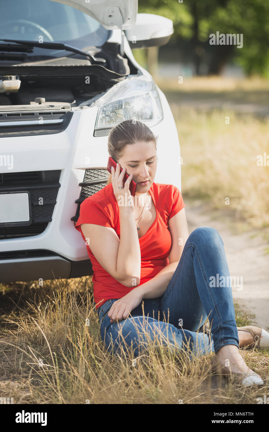 Triste jeune femme avec voiture cassée service appelant à son remorquage transports Banque D'Images