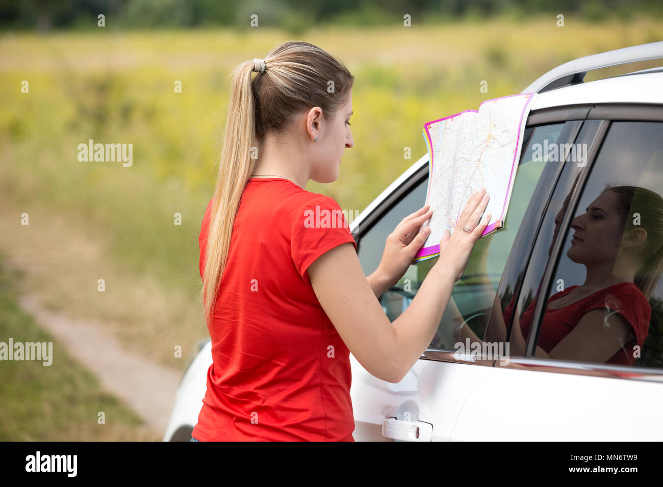 Young woman leaning on voiture et à la route à Banque D'Images