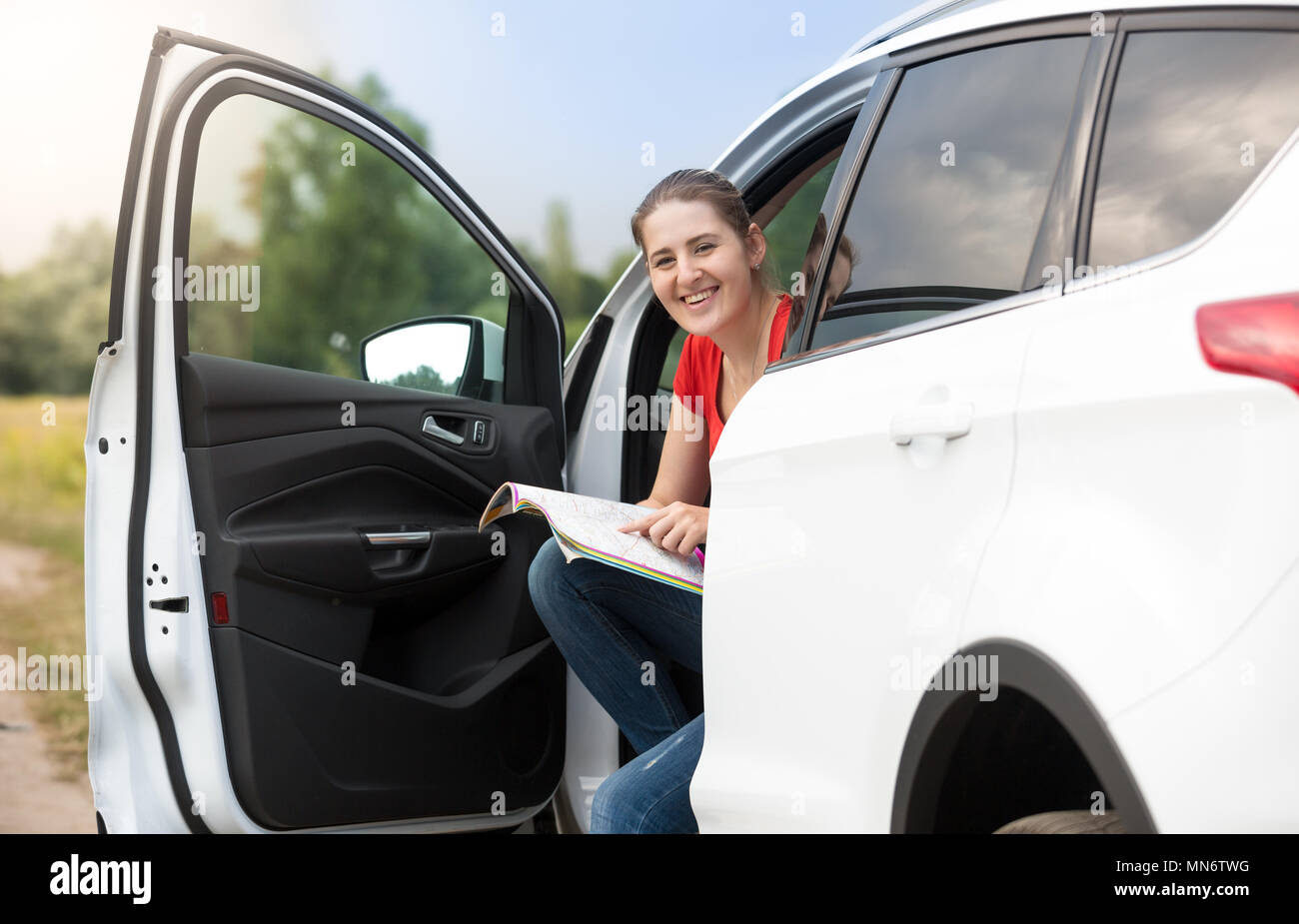 Portrait de jeune femme voyageant en voiture à la carte routière papier à Banque D'Images