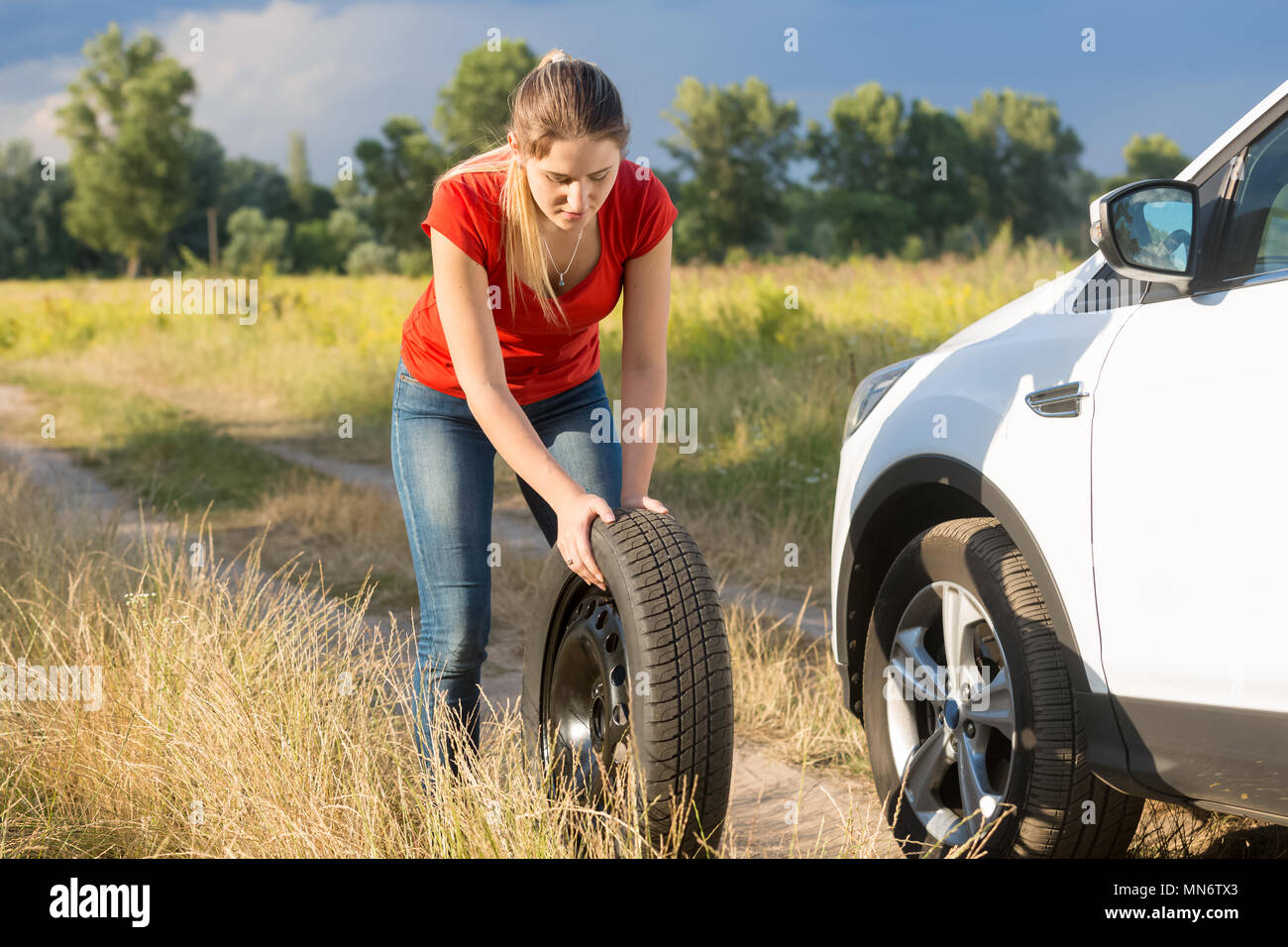 Jeune femme de roue de roulement pour son véhicule sur route de campagne Banque D'Images