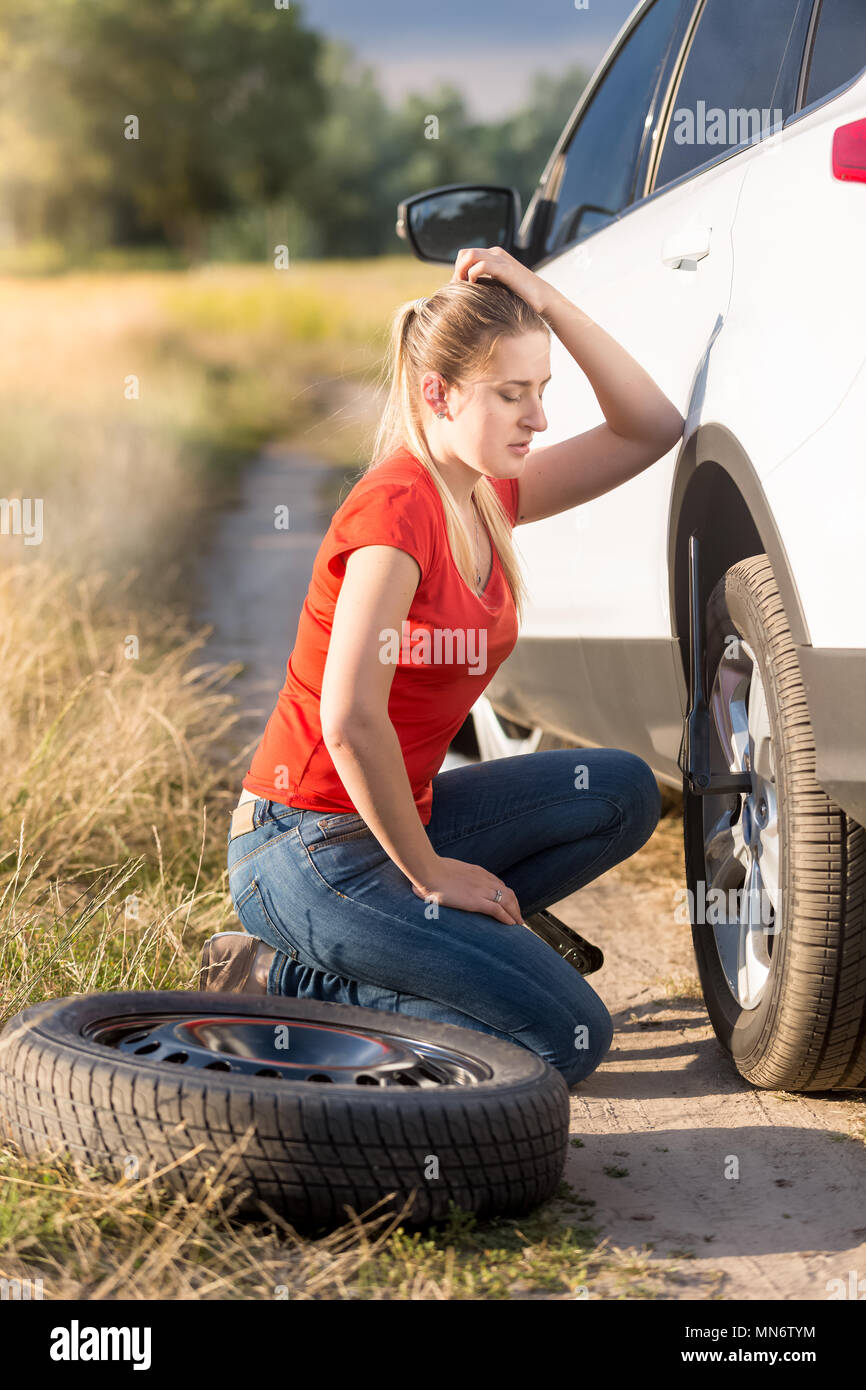 Jeune femme triste évolution télévision pneu de voiture avec les pièces de l'un dans le champ Banque D'Images