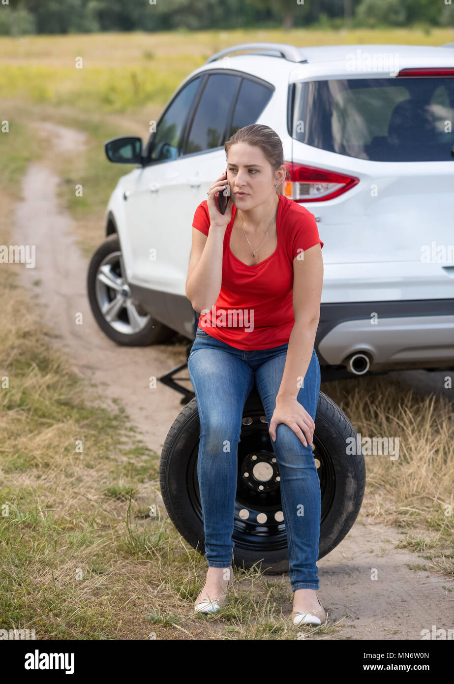 Jeune femme en colère a obtenu son pneu crevé et appelant à l'aide de service auto Banque D'Images
