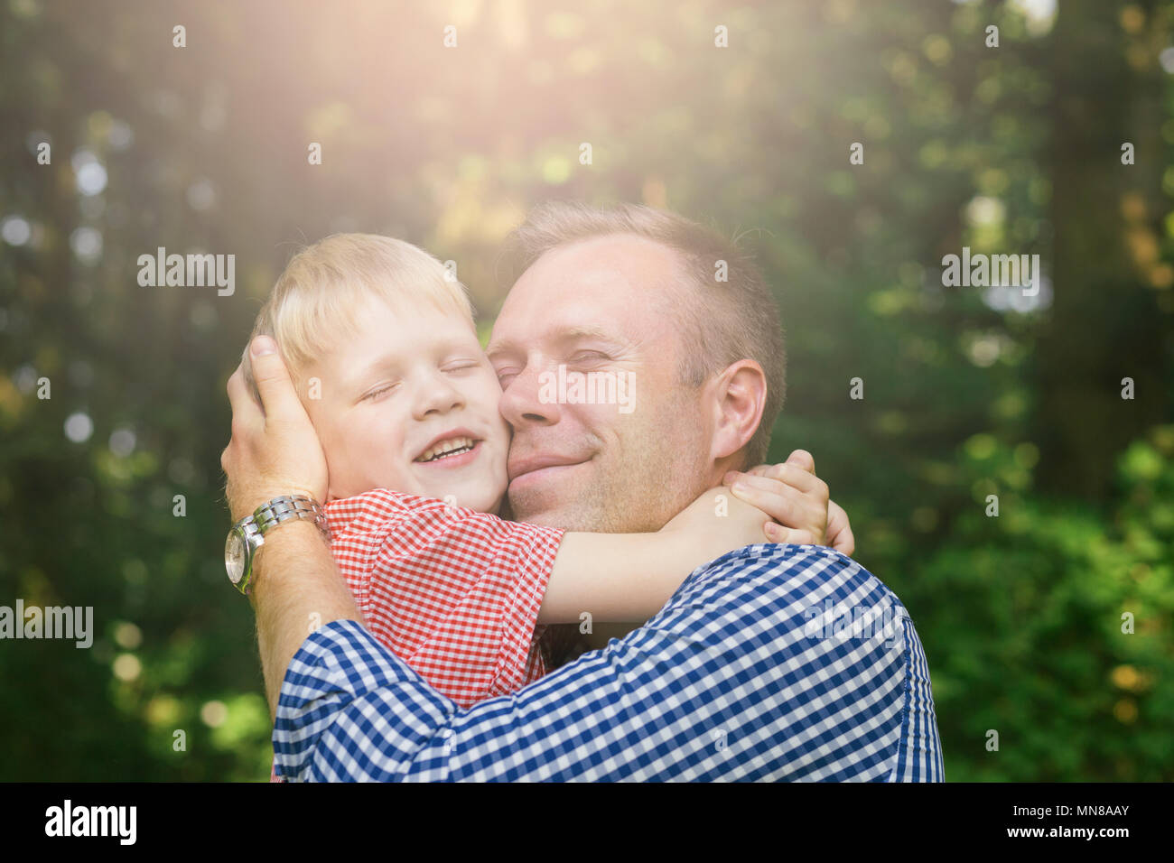 Père et fils hugging et souriant dans le jardin. Concept de la masculinité. Banque D'Images