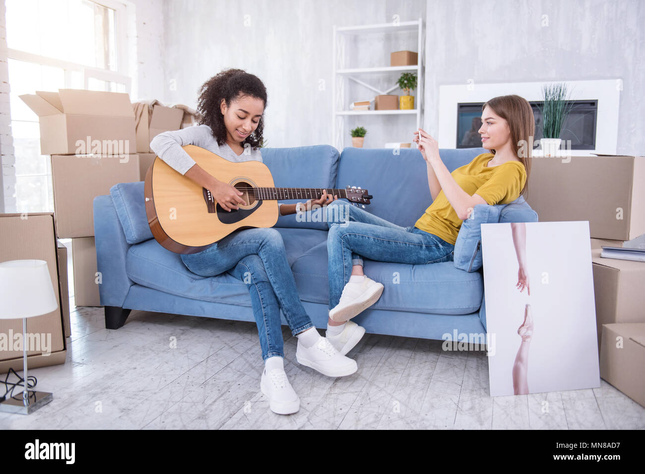 Jolie fille de filmer son ami jouer de la guitare pour son Banque D'Images