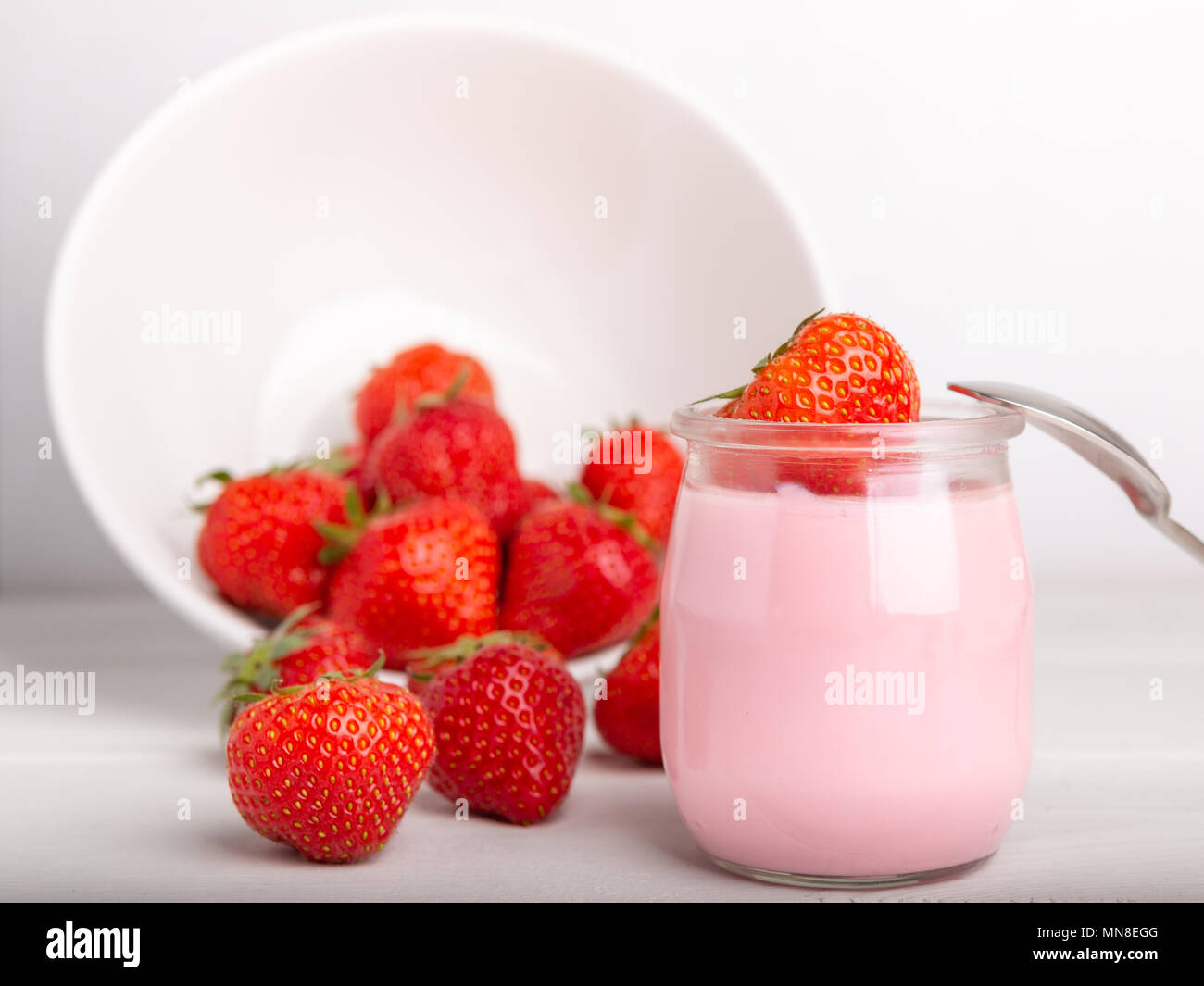 Avec la fraise yogourt aux fraises fraîchement préparés et une cuillère sur un fond blanc Banque D'Images