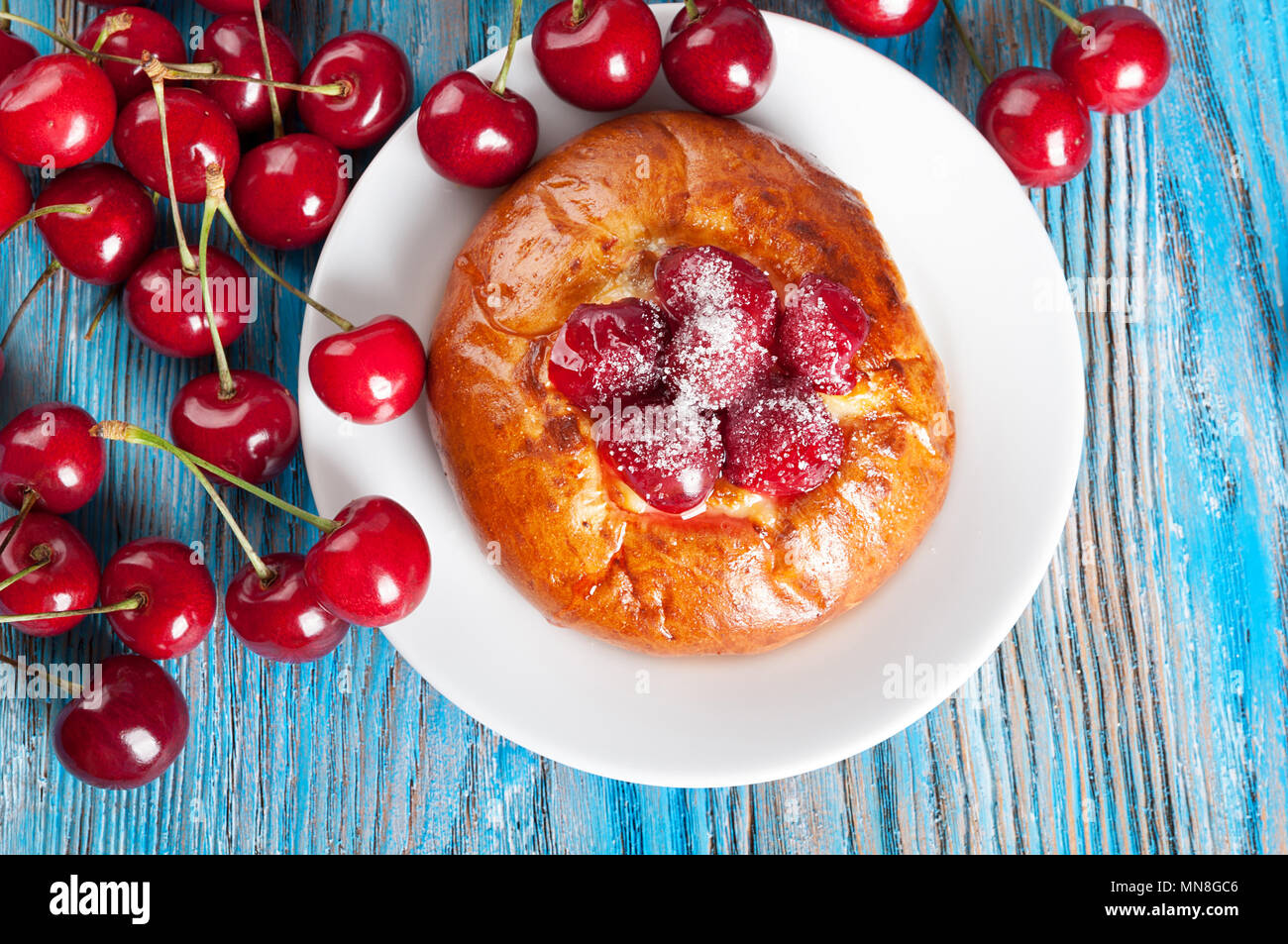 Pain maison avec sweet cherry dans un plat blanc bleu sur un fond de bois. Vue d'en haut. Banque D'Images