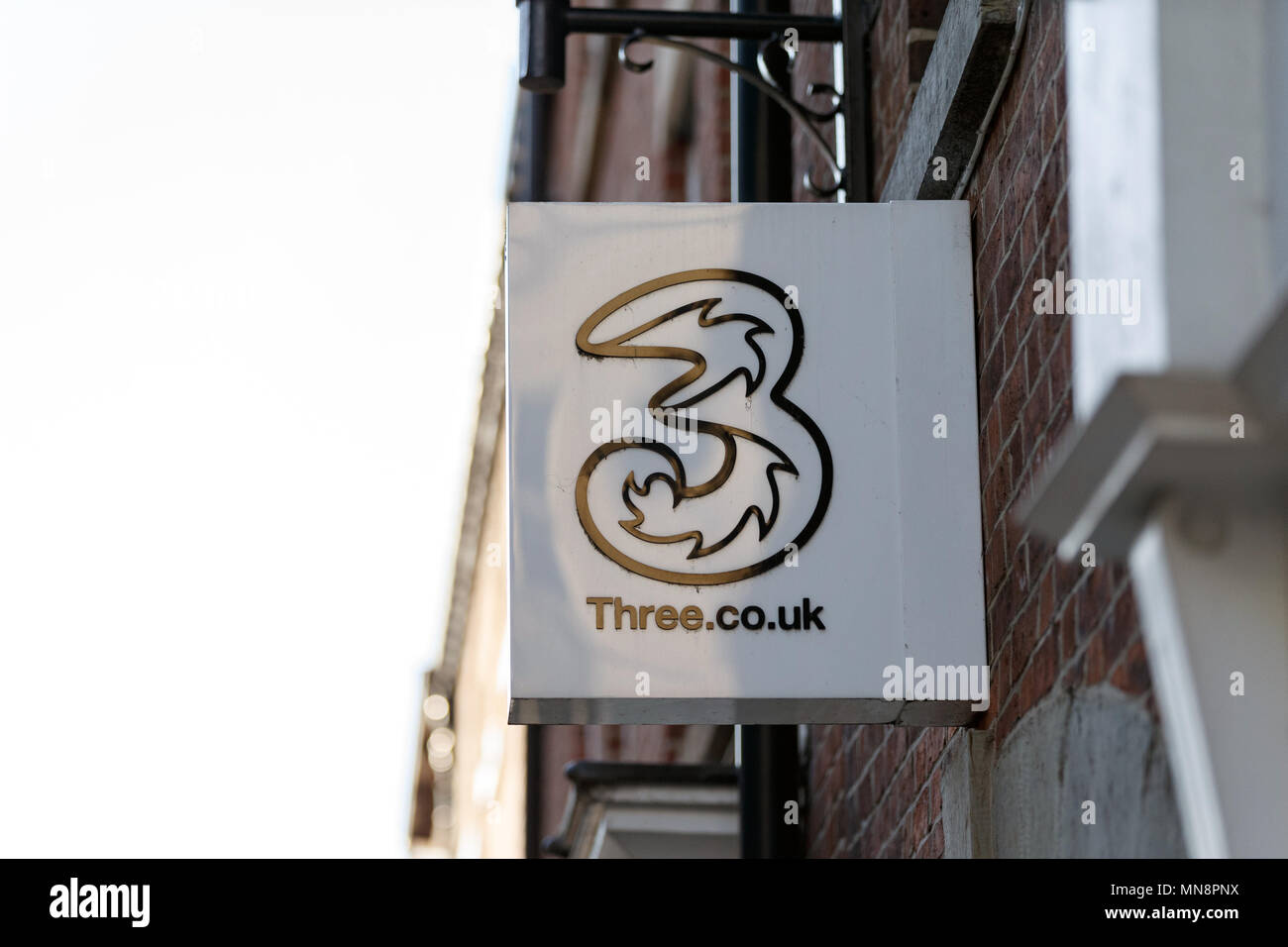 Une succursale de la rue haute de fournisseur de réseau mobile trois au Royaume-Uni / logo trois, trois, trois signes high street. Banque D'Images