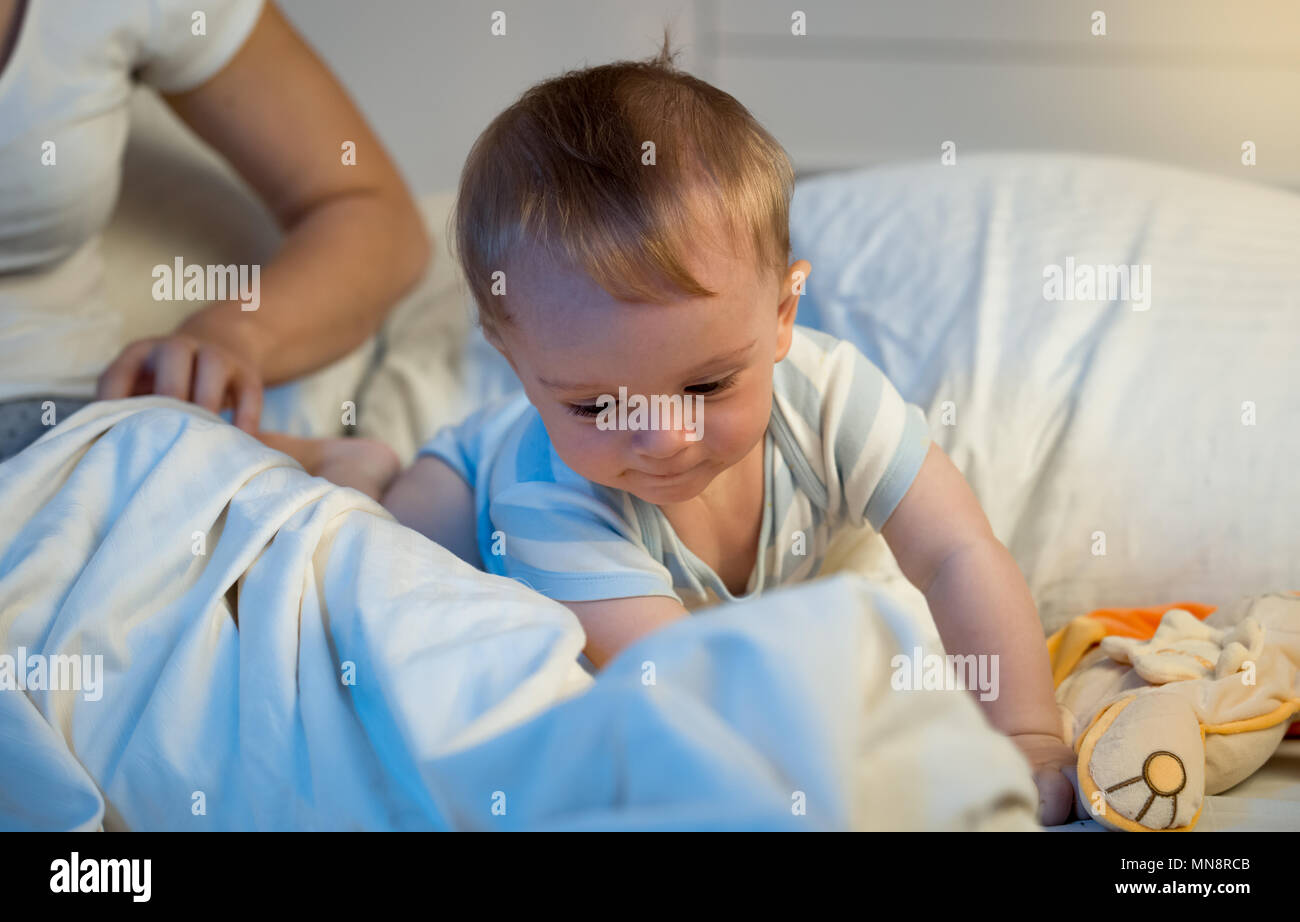 Portrait de 9 mois adorable baby boy crawling on lit la nuit Banque D'Images