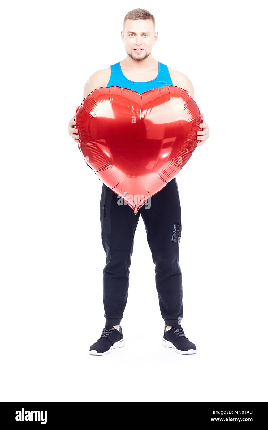 Portrait d'athlète holding big red heart-shaped balloon isolated on white Banque D'Images