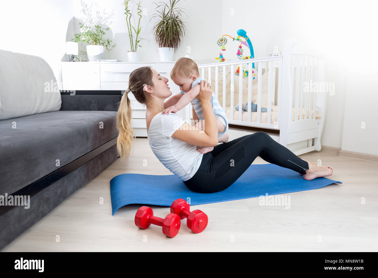 Belle jeune femme pratiquant le yoga à la maison avec son petit garçon Banque D'Images