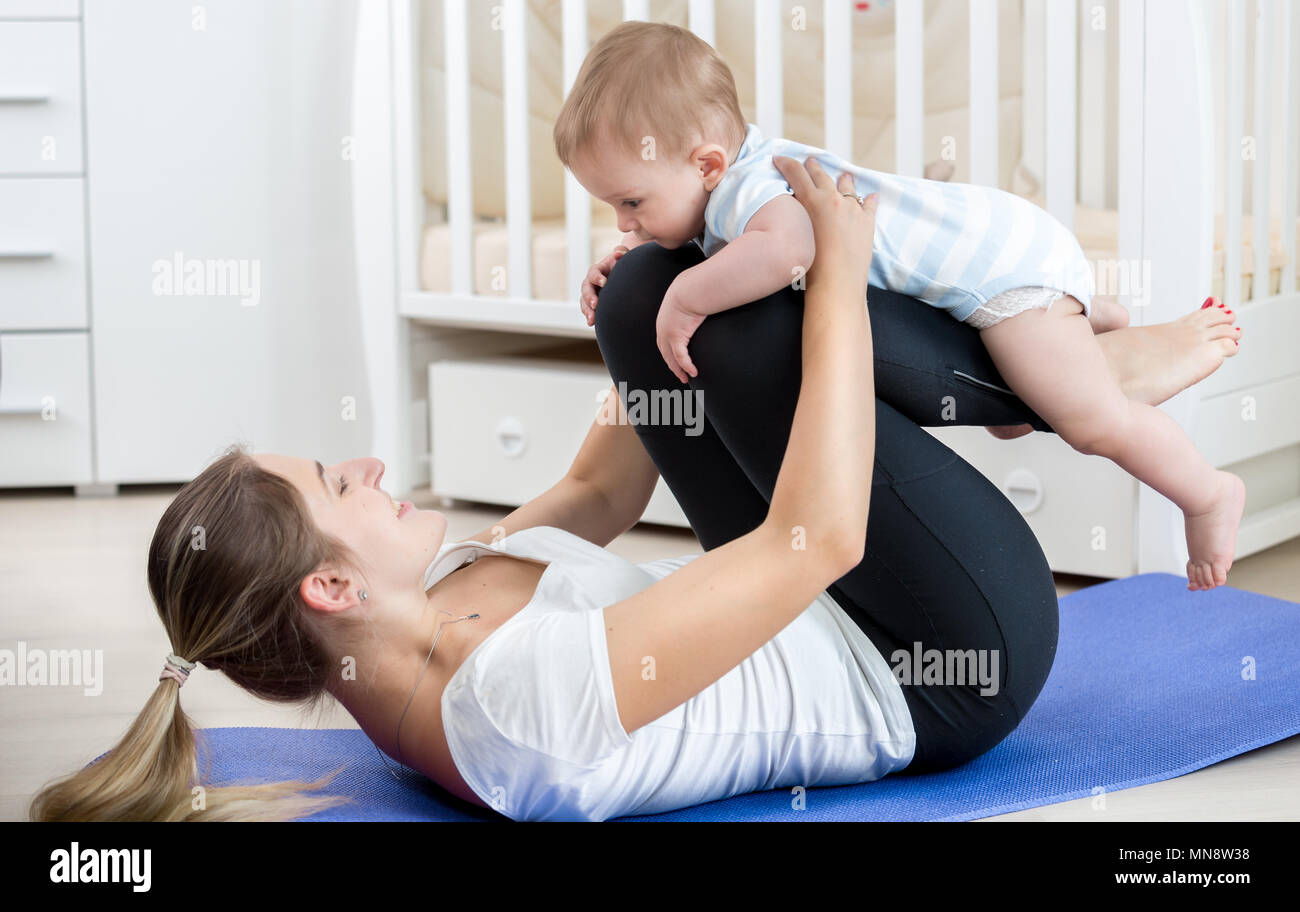 Portrait of smiling young woman practicing yoga et remise en forme avec son bébé garçon Banque D'Images