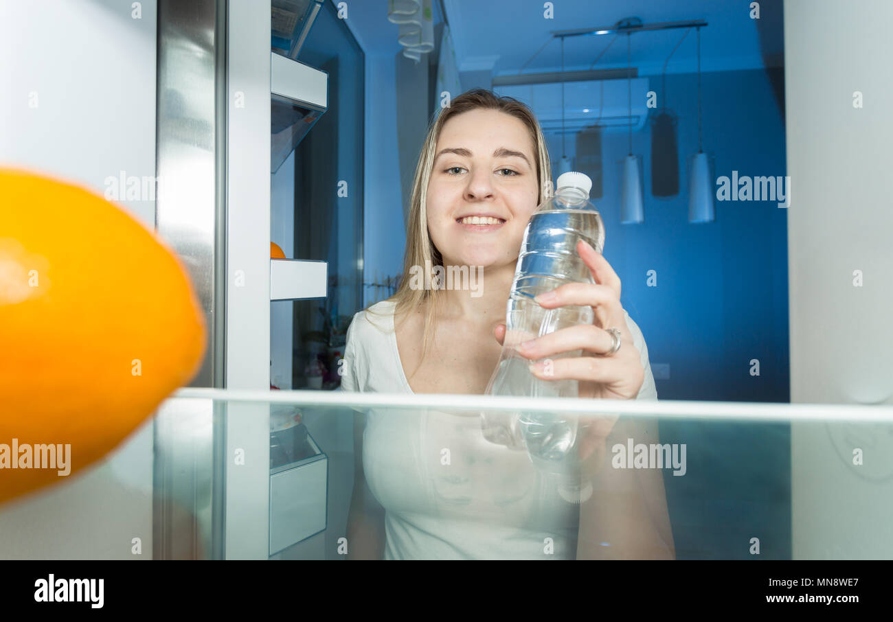 Portrait de jeune femme en tenant une bouteille d'eau de la nuit au réfrigérateur). Banque D'Images