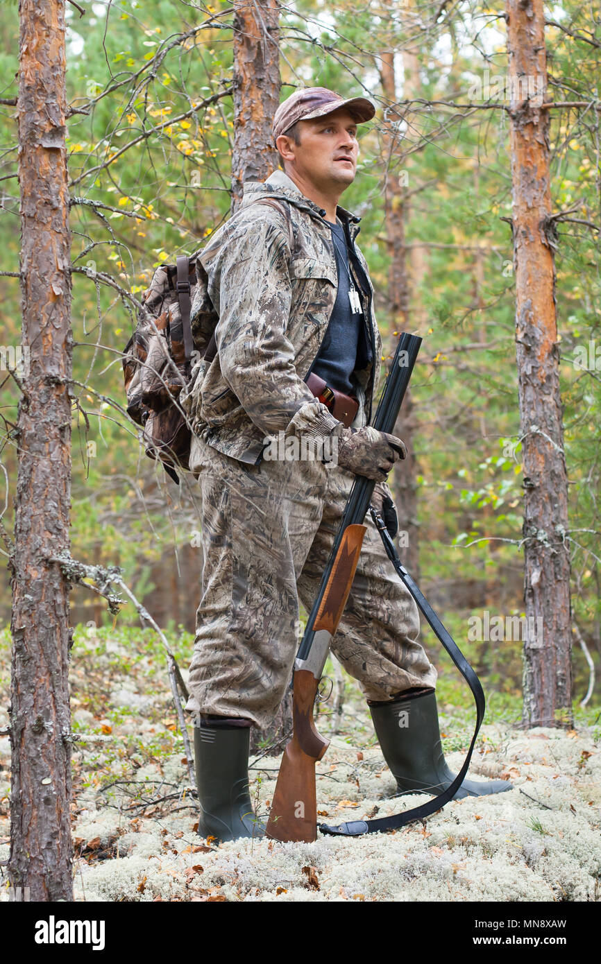 Hunter de camouflage avec fusil de chasse dans la forêt de pins Banque D'Images