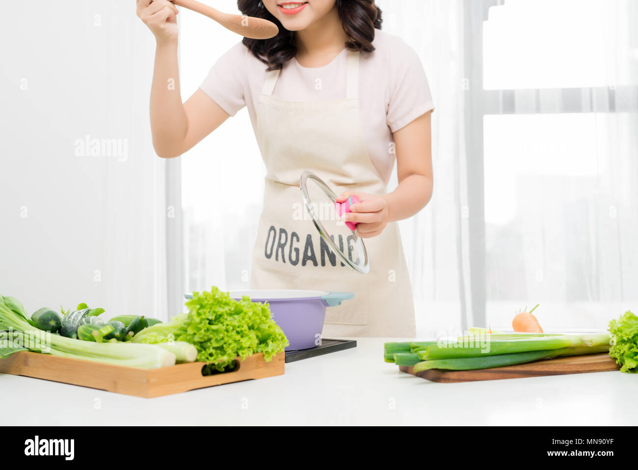 Portrait de belle jeune femme cuisson de la soupe aux légumes à la maison. Banque D'Images