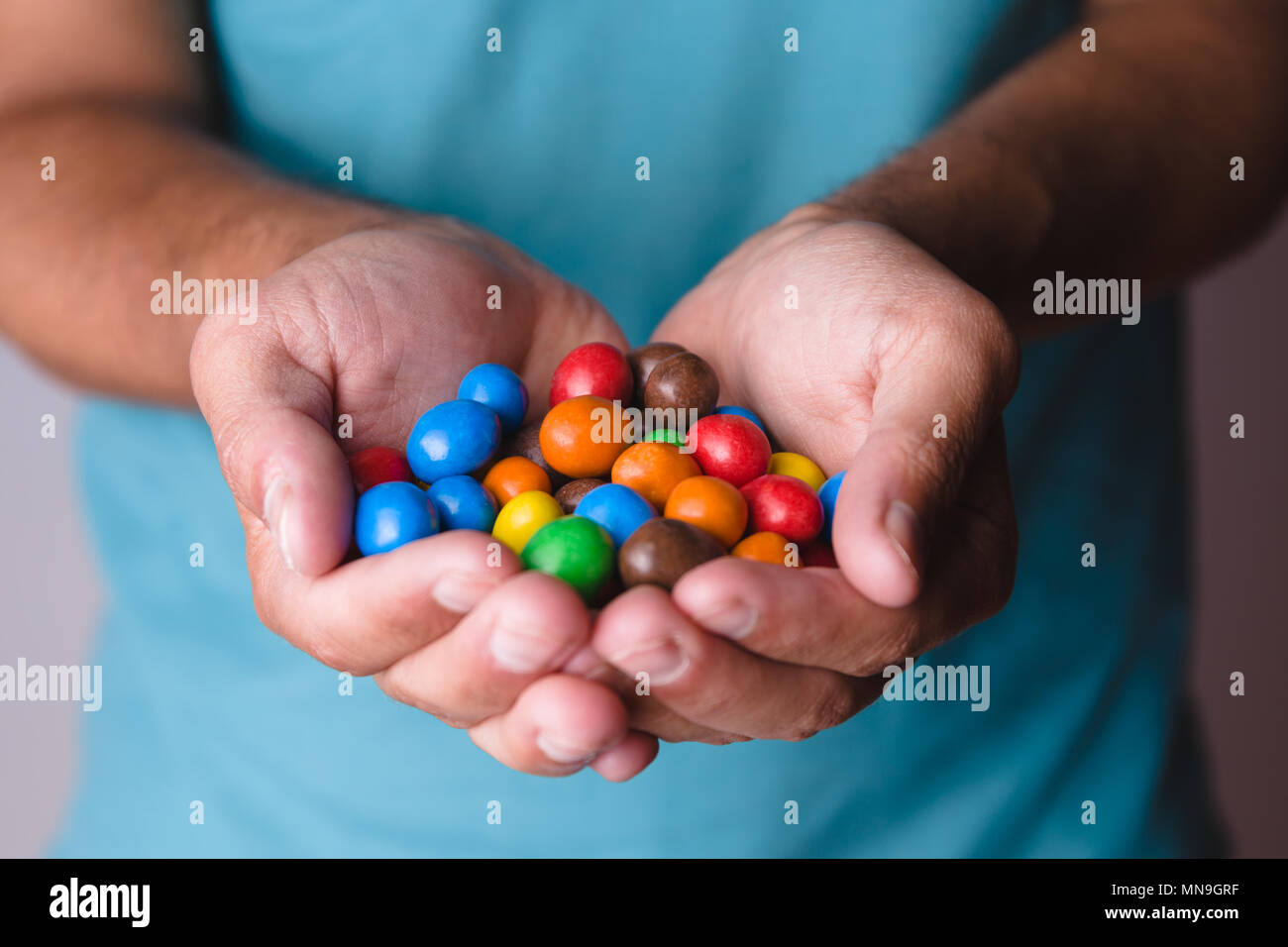 Homme de race blanche holding bonbons colorés Banque D'Images