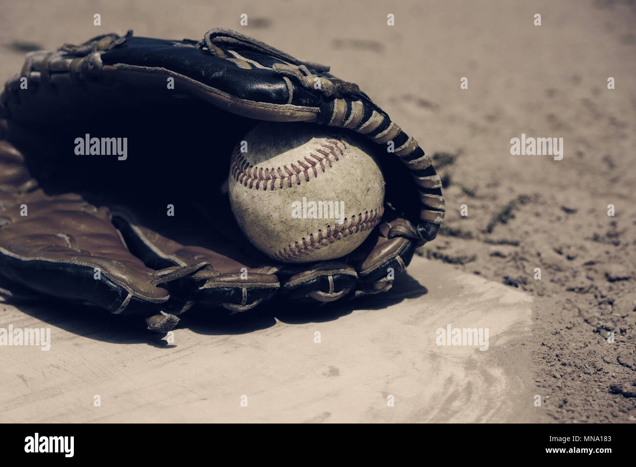 Les joueurs de baseball Vintage glove laying on homeplate, terrain de balle saleté en arrière-plan. Banque D'Images
