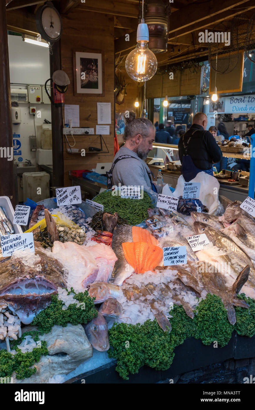 Un poissonnier sur un étal à Borough Market à Londres la vente de fruits de mer fraîchement pêchés et des crustacés. Poisson frais pour une alimentation saine à marché. Banque D'Images