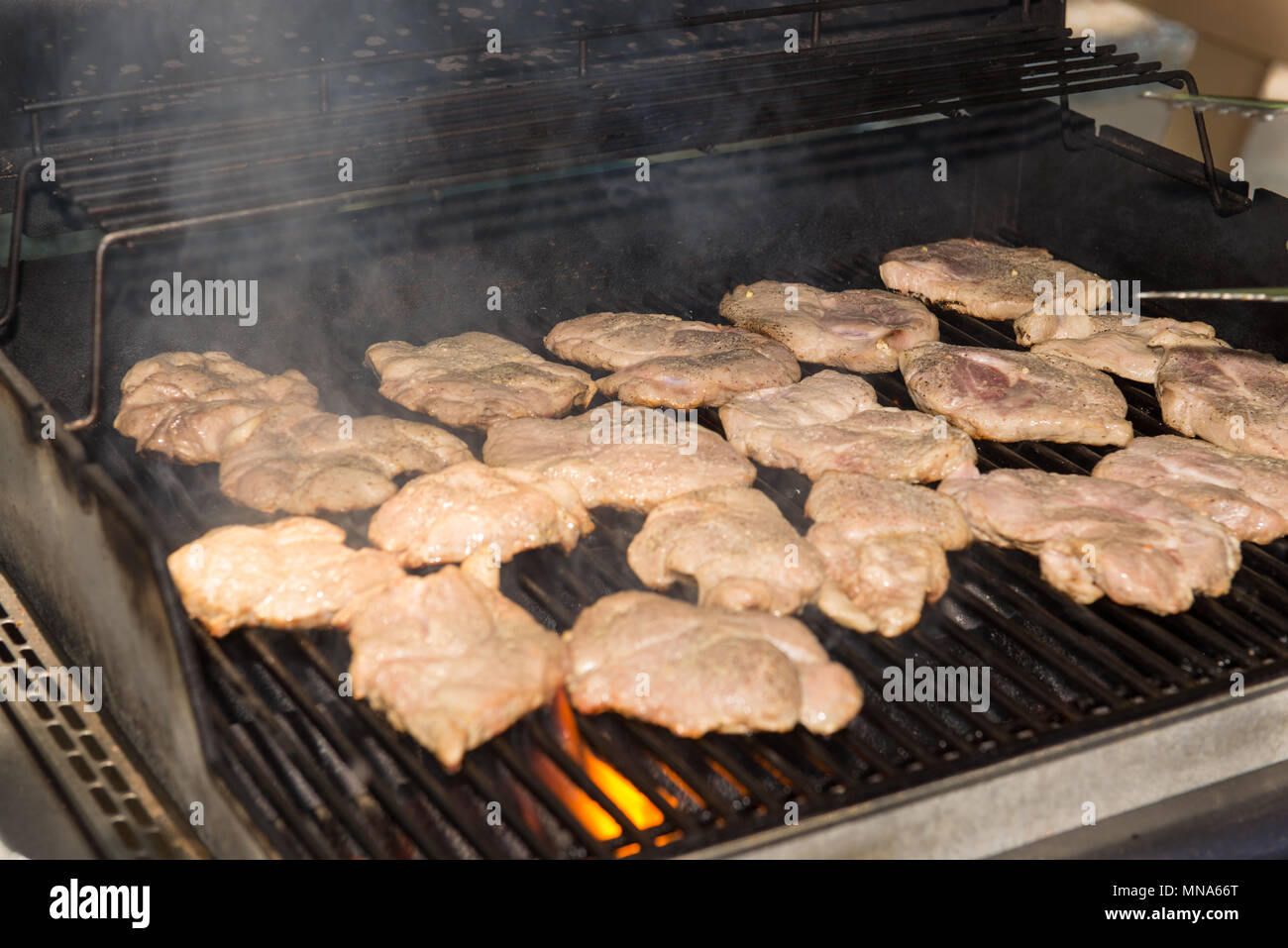 Plusieurs cuisson viande steaks de porc sur un grill avec de la fumée et les flammes. Banque D'Images