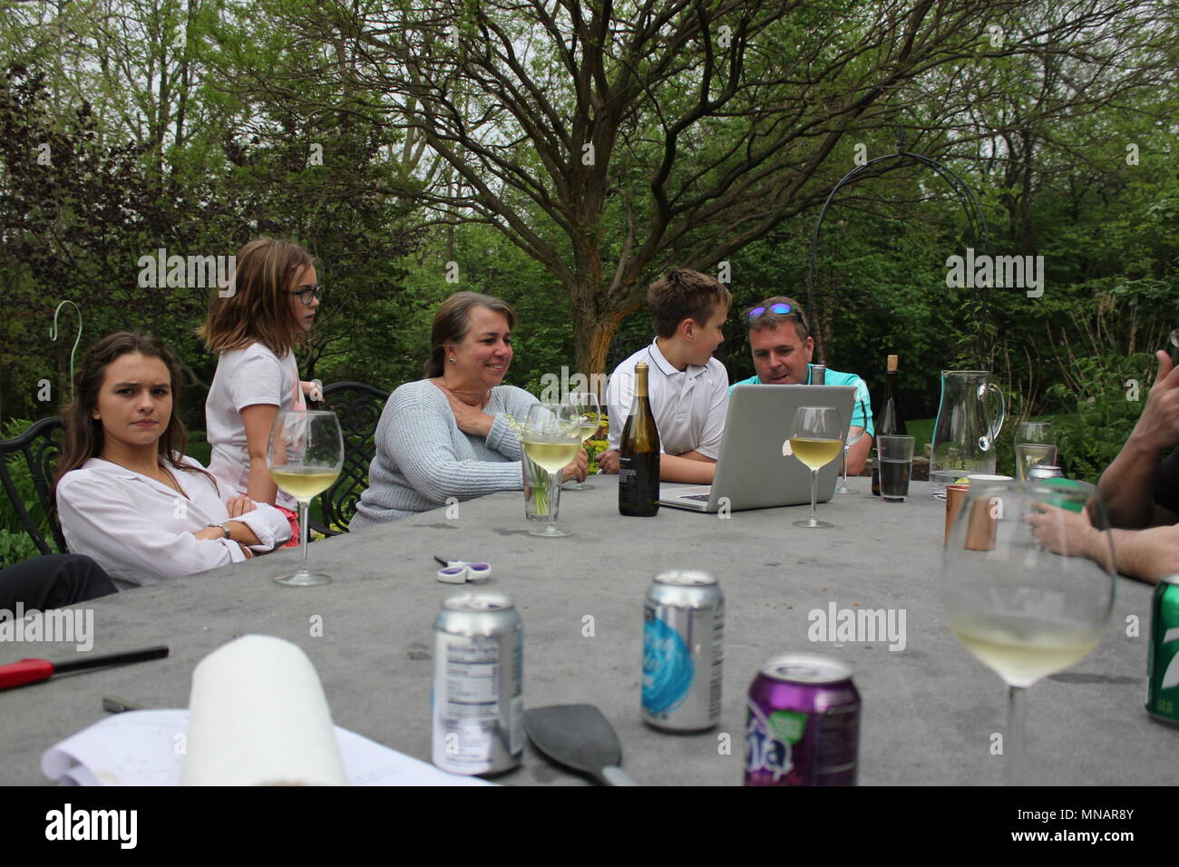 Groupe des gens rire et à la recherche à l'ordinateur tout en étant assis sur une terrasse extérieure. Banque D'Images