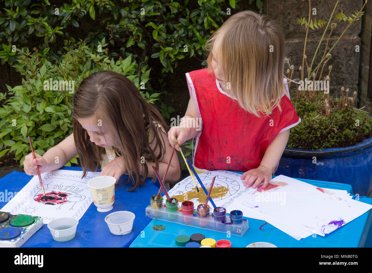 Deux ans, fille de quatre ans, soeur photos peinture, modèles avec les peintures à l'aquarelle en jardin, obtenir de la peinture sur les mains. Banque D'Images