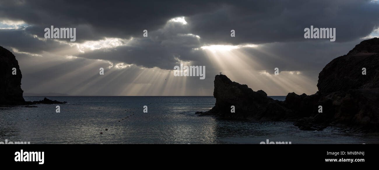 LANZAROTE, îles Canaries, Espagne : rayons de soleil à travers un nuage sur l'horizon à plage de Papagayo. Banque D'Images