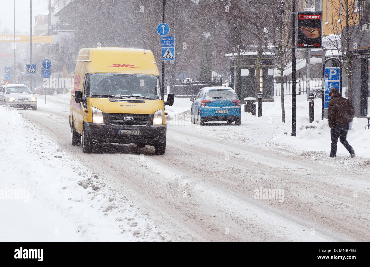 Karlstad, Suède - 30 janvier 2014 : Une livraison de colis DHL jaune van roulant sur la rue Ostra Torgatan avec conditions des routes en hiver dans la ville cen Banque D'Images