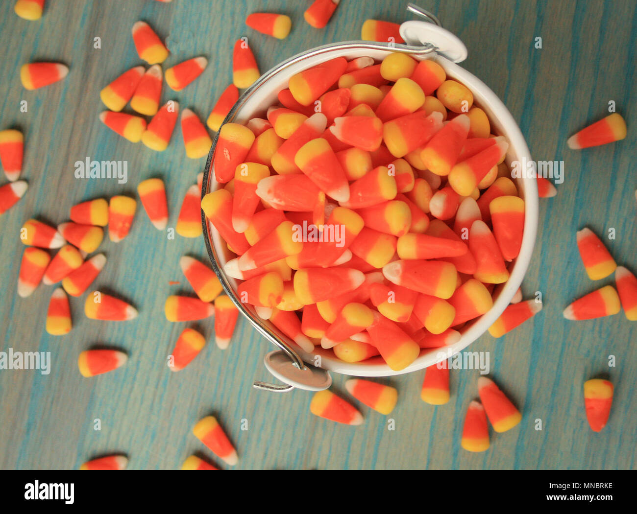 Vue de dessus de candy corns bonbons d'Halloween à l'intérieur d'un seau blanc. Aussi une bande en vertu de l'entourant le godet sur une table rustique en bois vert. Tout autour de lui Banque D'Images