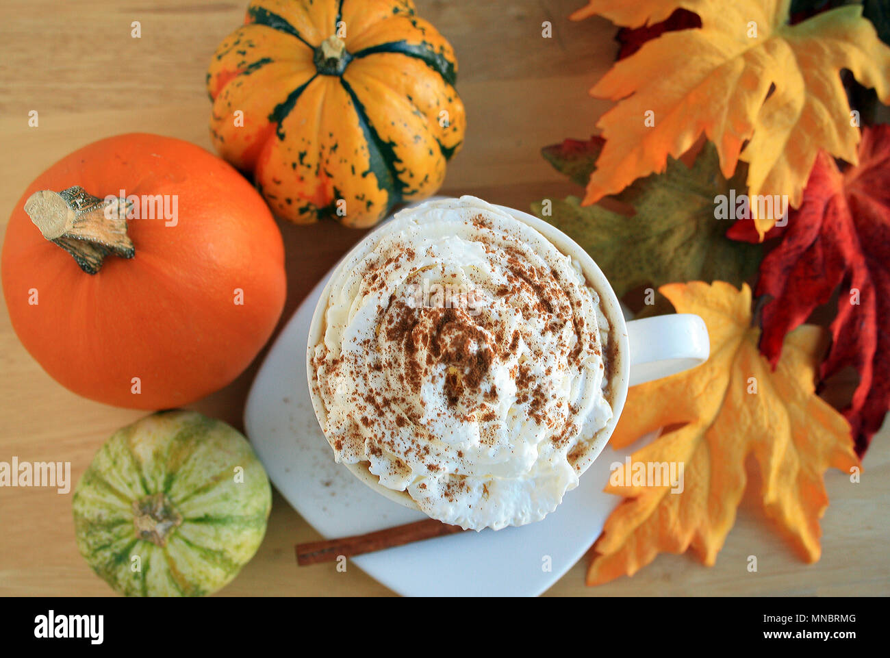 Tasse à café cappuccino vue d'en haut. Avec de la Cannelle et mousse. Entouré de citrouilles et courges automne feuilles autour de la tasse. Mug avec le bâton de cannelle. Banque D'Images