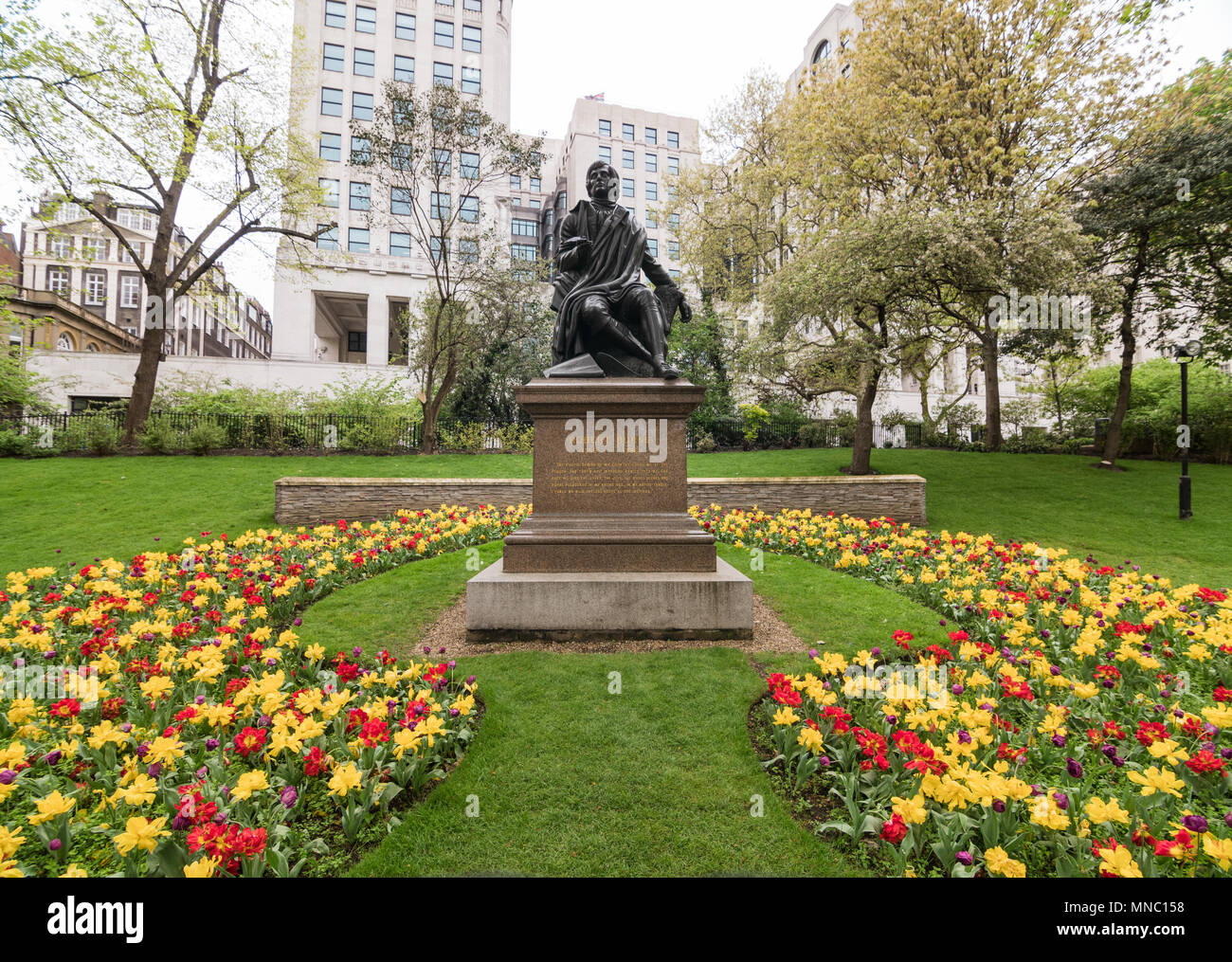 Statue du poète Robert Burns entourée de fleurs à Embankment Gardens, Londres. Banque D'Images