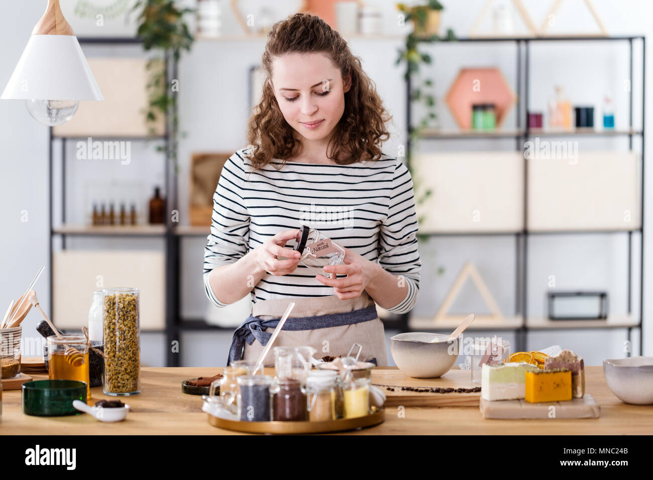 Vendeuse de produits naturels un pot en verre pour dévisser la crème organique Banque D'Images