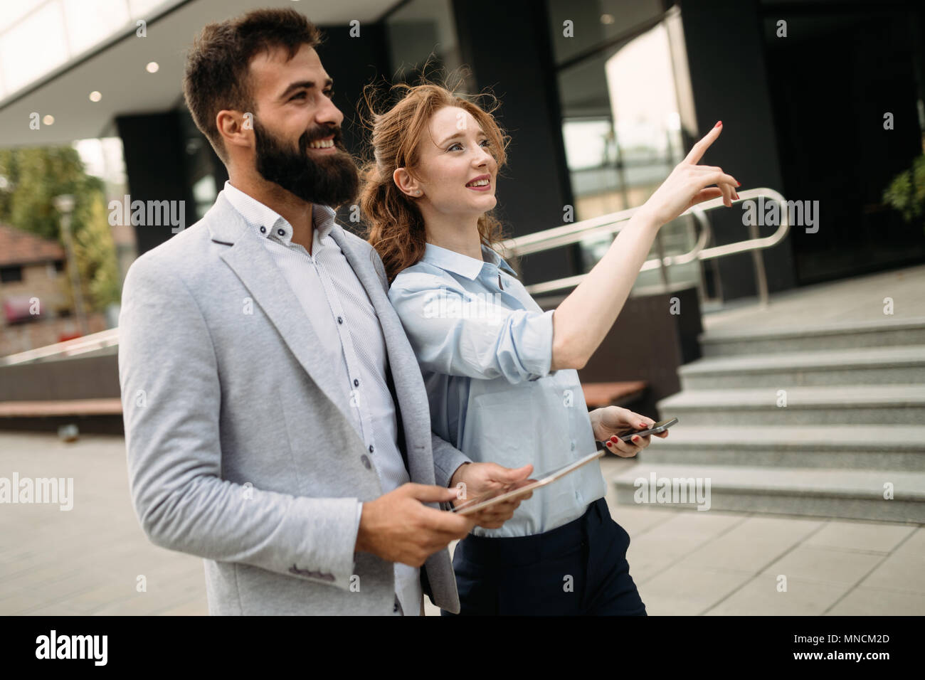 Business man and woman working outdoors with tablet computer in front of office Banque D'Images