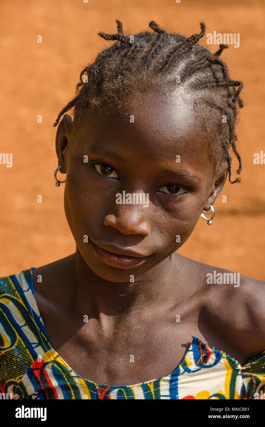 Kindia, Guinée - 28 décembre 2013 : Portrait de jeune fille africaine non identifiés avec route de terre en arrière-plan Banque D'Images