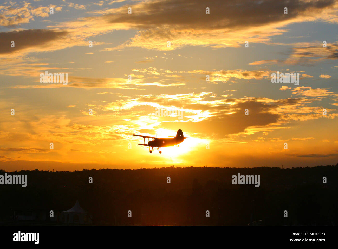 Un biplan survolant le ciel tandis que le coucher du soleil derrière elle. Moment de soleil. Banque D'Images