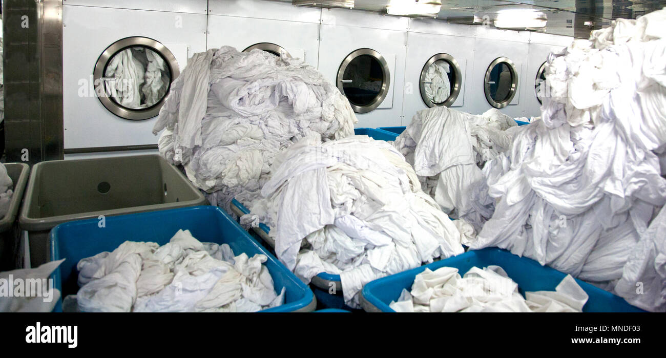 Des draps blancs en grands tas prêts à être lavés ou séché dans les machines de taille industrielle Banque D'Images