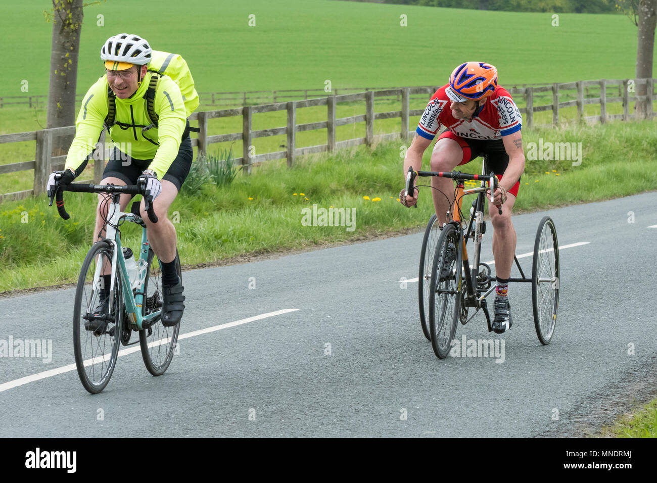 Close-up de deux hommes matures en vélo, pédalant & vélo le long chemin de campagne pittoresque, 1 circonscription un tricycle - près de Ilkley, North Yorkshire, Angleterre, Royaume-Uni. Banque D'Images