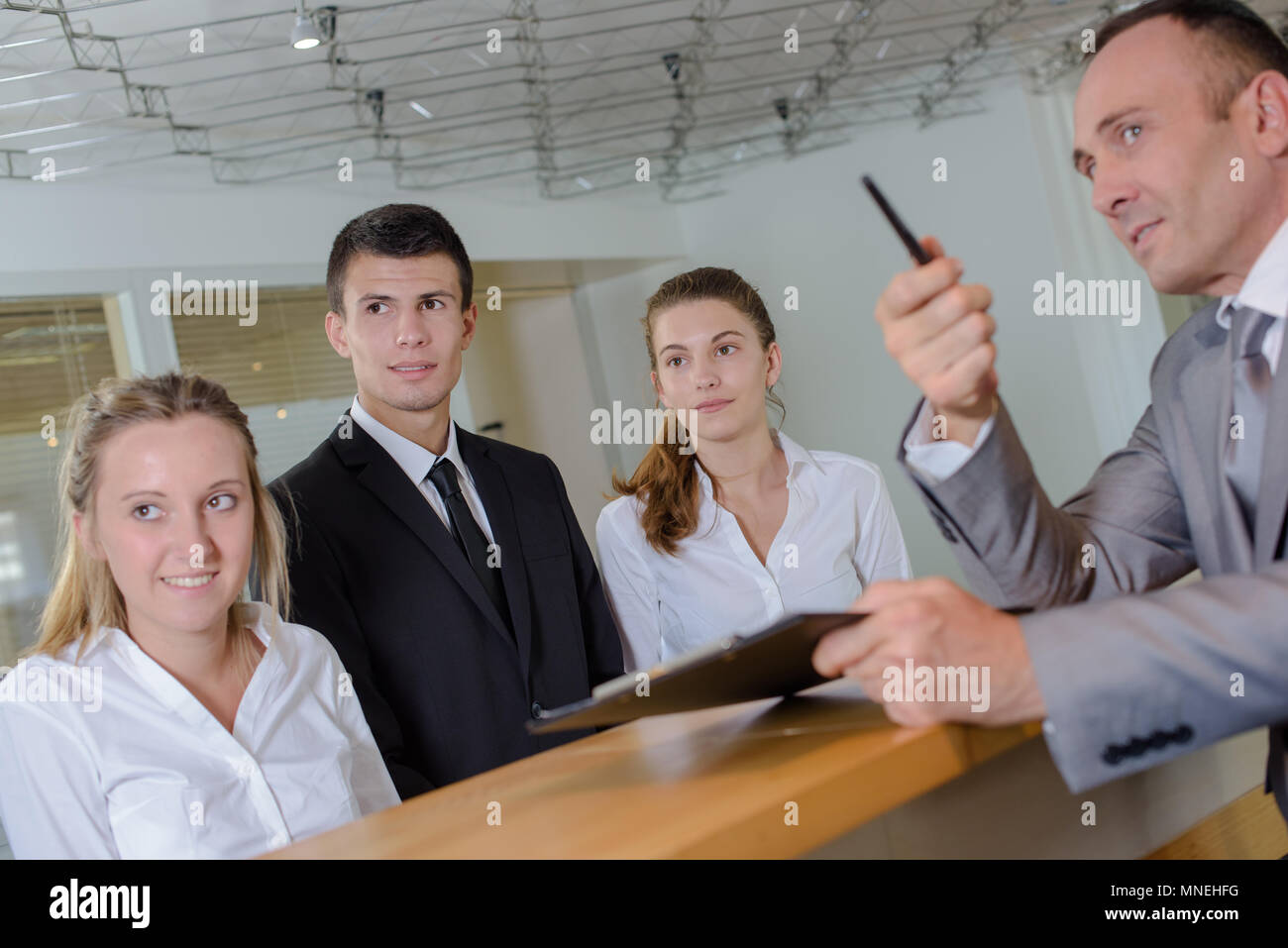 L'homme à la réception avec de jeunes fonctionnaires pointant vers la gauche Banque D'Images