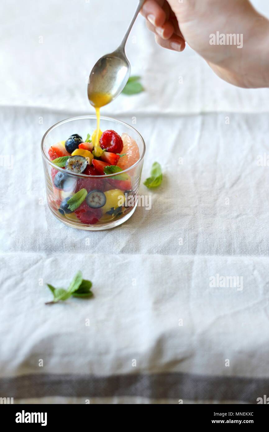 Une salade de fruits d'être arrosé dans un basilic et menthe sirop d'agrumes Banque D'Images