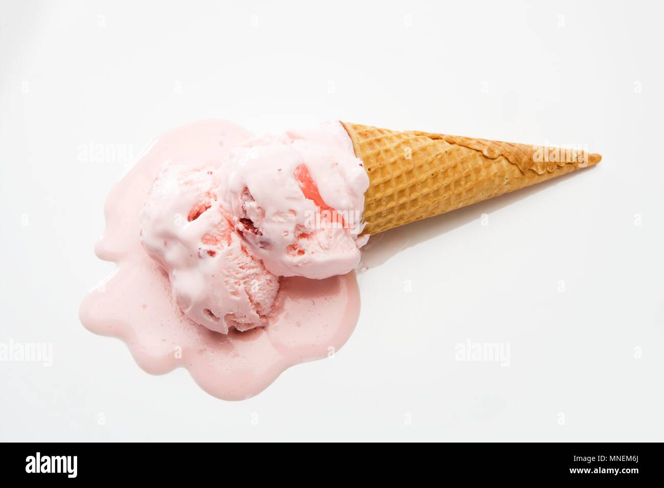 Cornet de crème glacée aux fraises fondant sur un fond blanc Banque D'Images