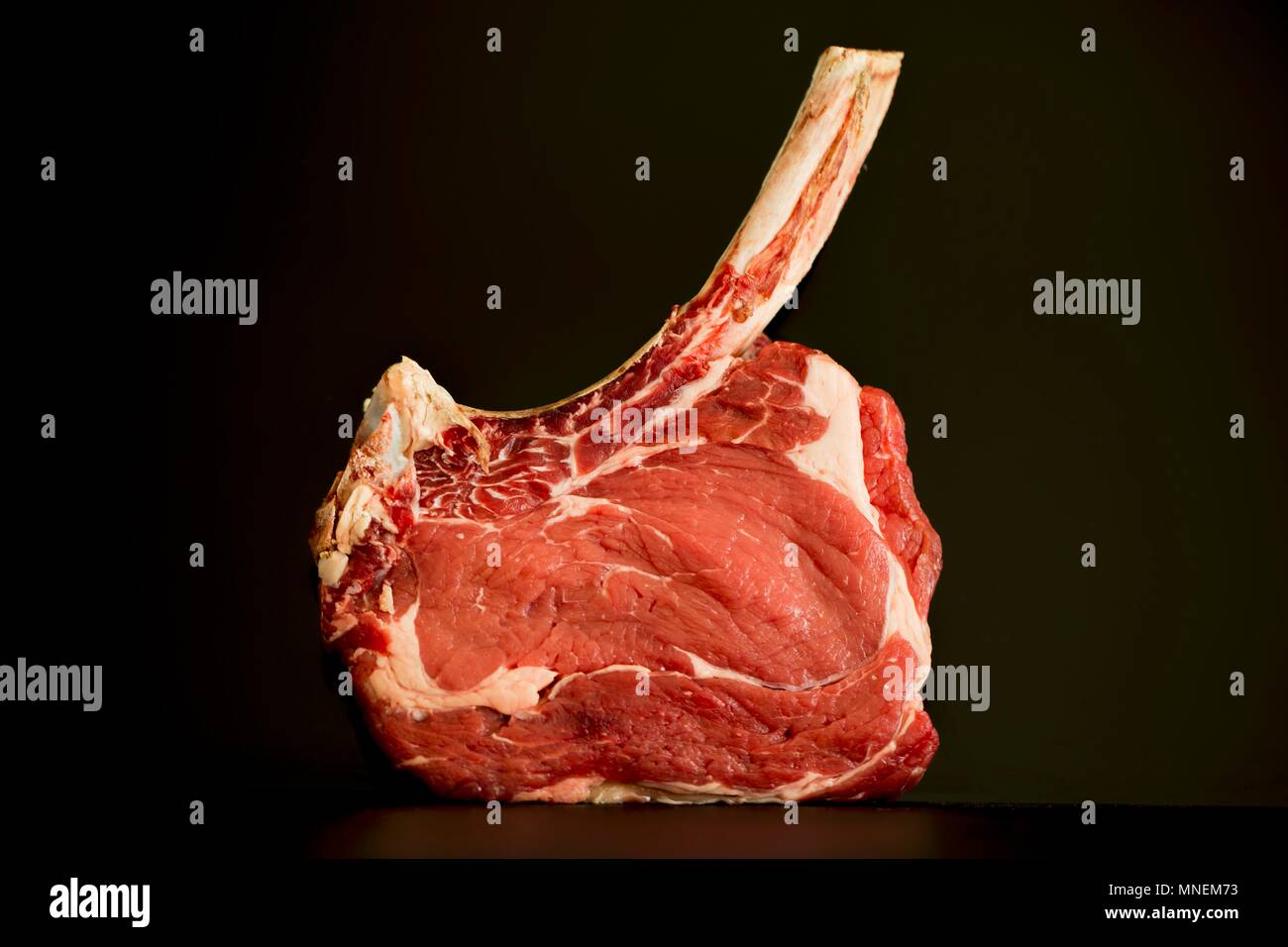 Steak de faux-filet avec un os long sur une surface sombre Banque D'Images Steak de faux-filet avec un os long sur une surface sombre Banque D'Images