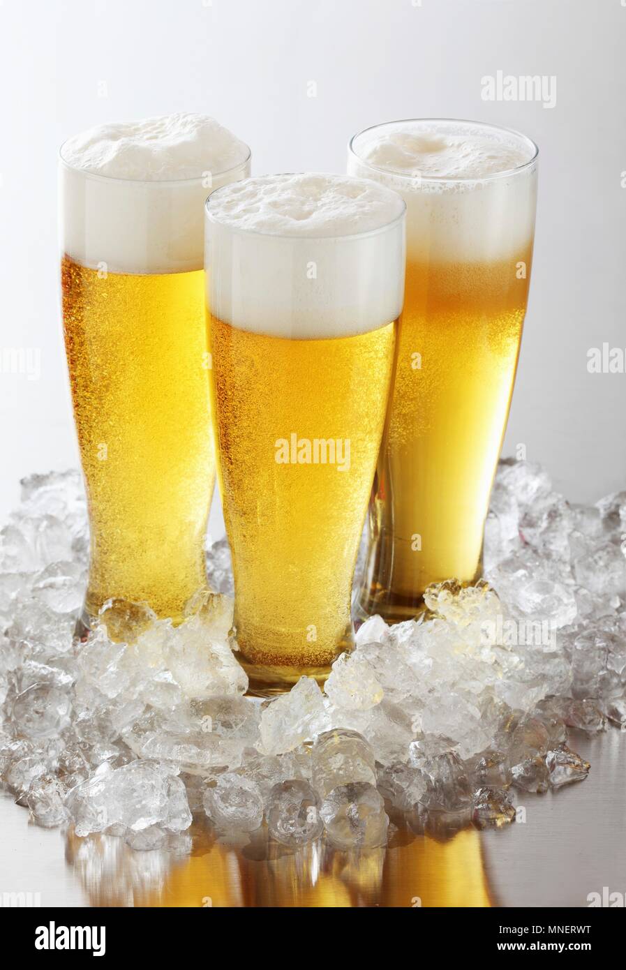 Trois verres de bière avec de la mousse sur de la glace concassée Banque D'Images