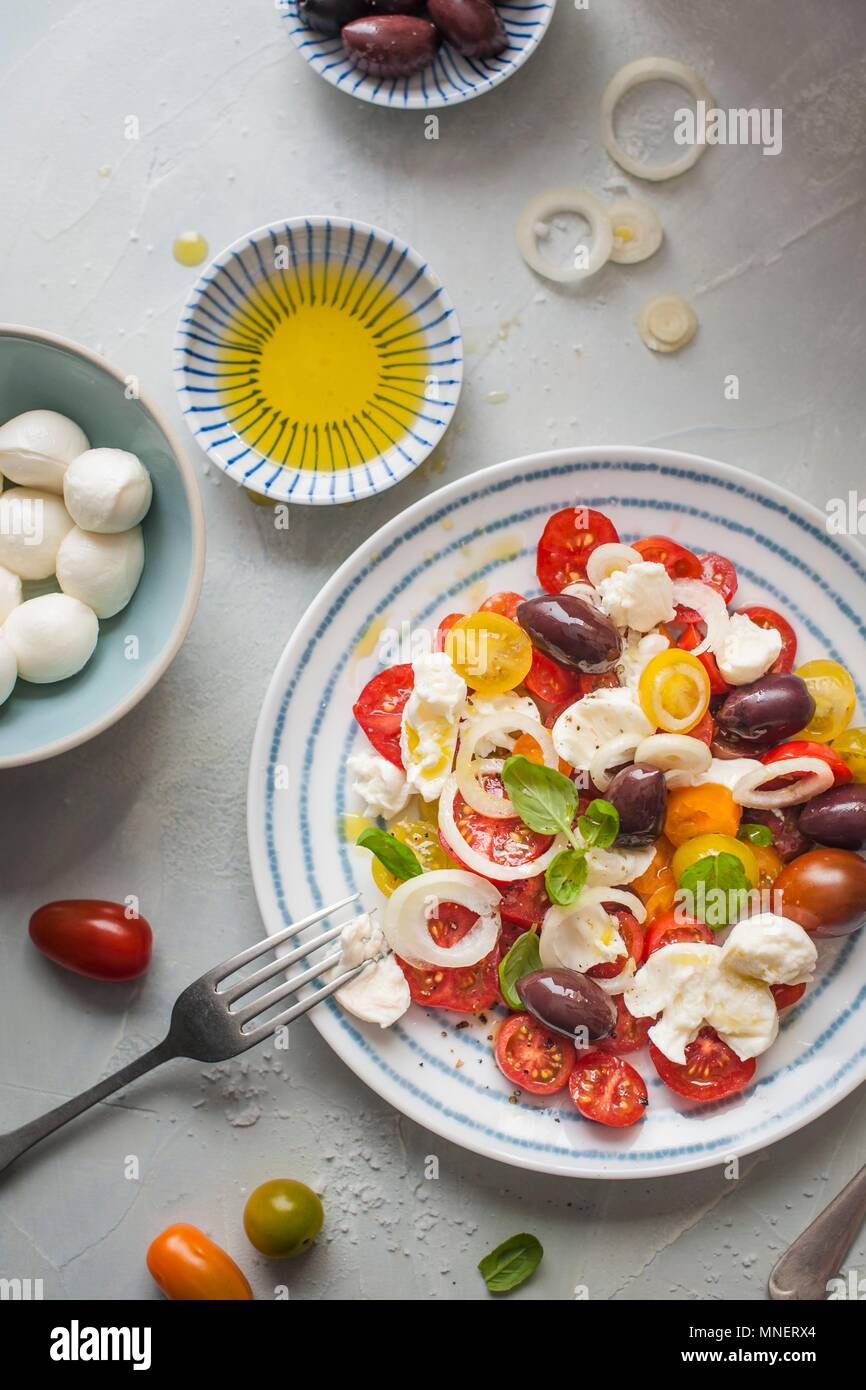 Salade de tomates et mozzarella avec des olives, l'oignon, le basilic et l'huile d'olive Banque D'Images