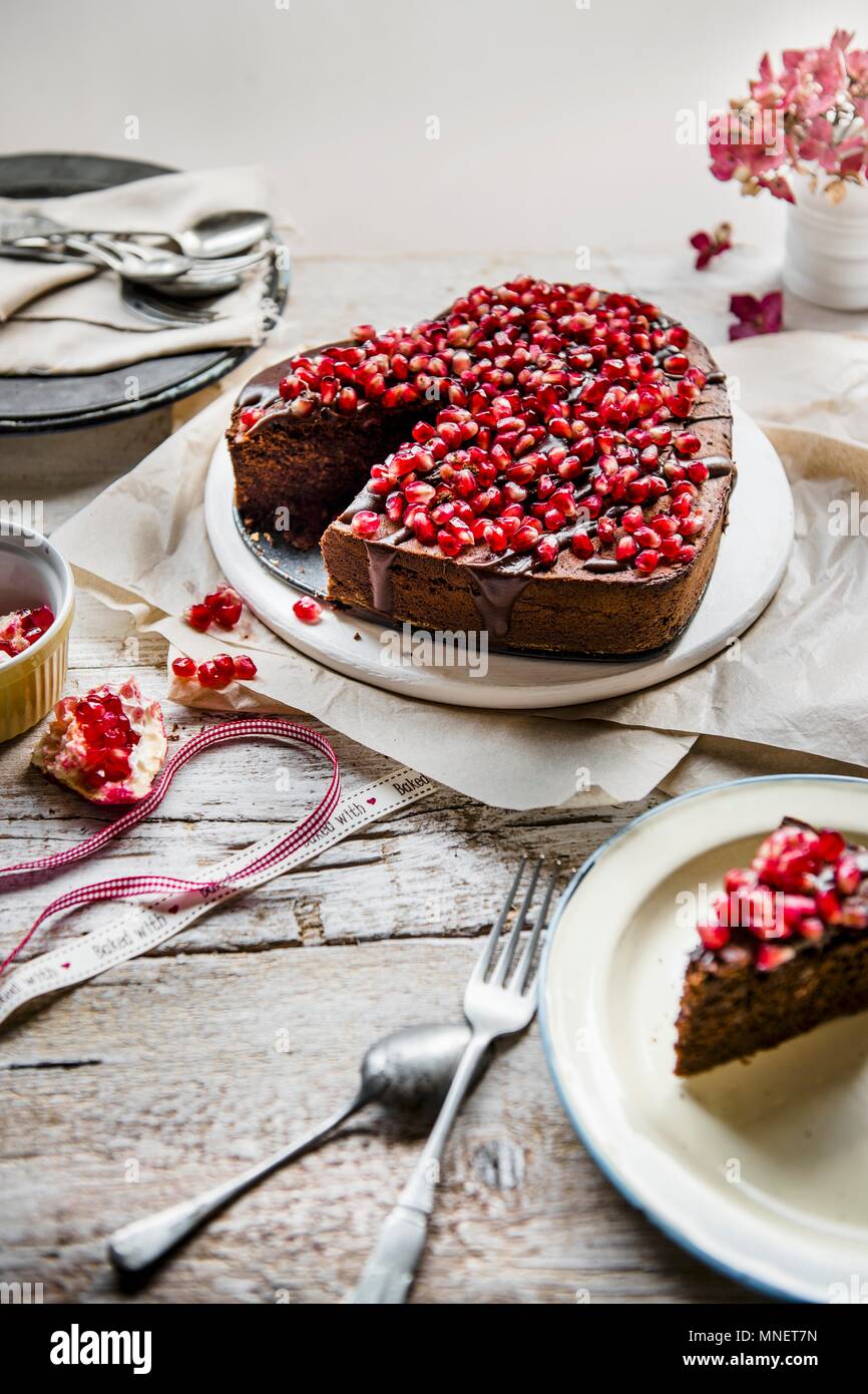 Gâteau au chocolat en forme de coeur avec lustre de chocolat et graines de grenade Banque D'Images