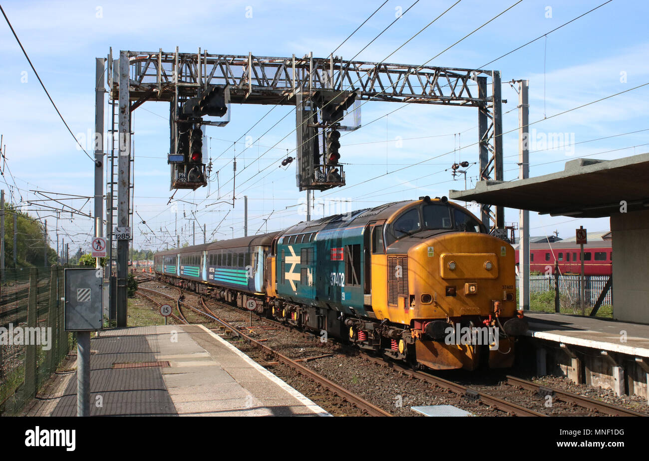 Diesel-électrique de classe 37 loco dans BR grand logo bleu livery entrée Comunidad de la gare avec un train de voyageurs, les entraîneurs en DRS Livery. Banque D'Images