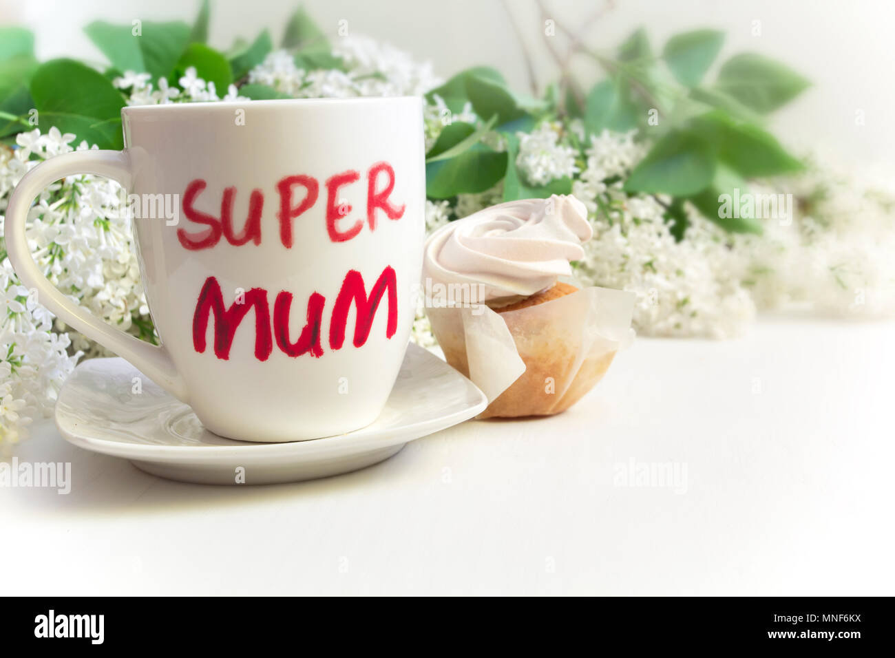 Concept de la fête des mères. Mug avec l'inscription 'Super maman', cupcake et lilas fleurs. Banque D'Images