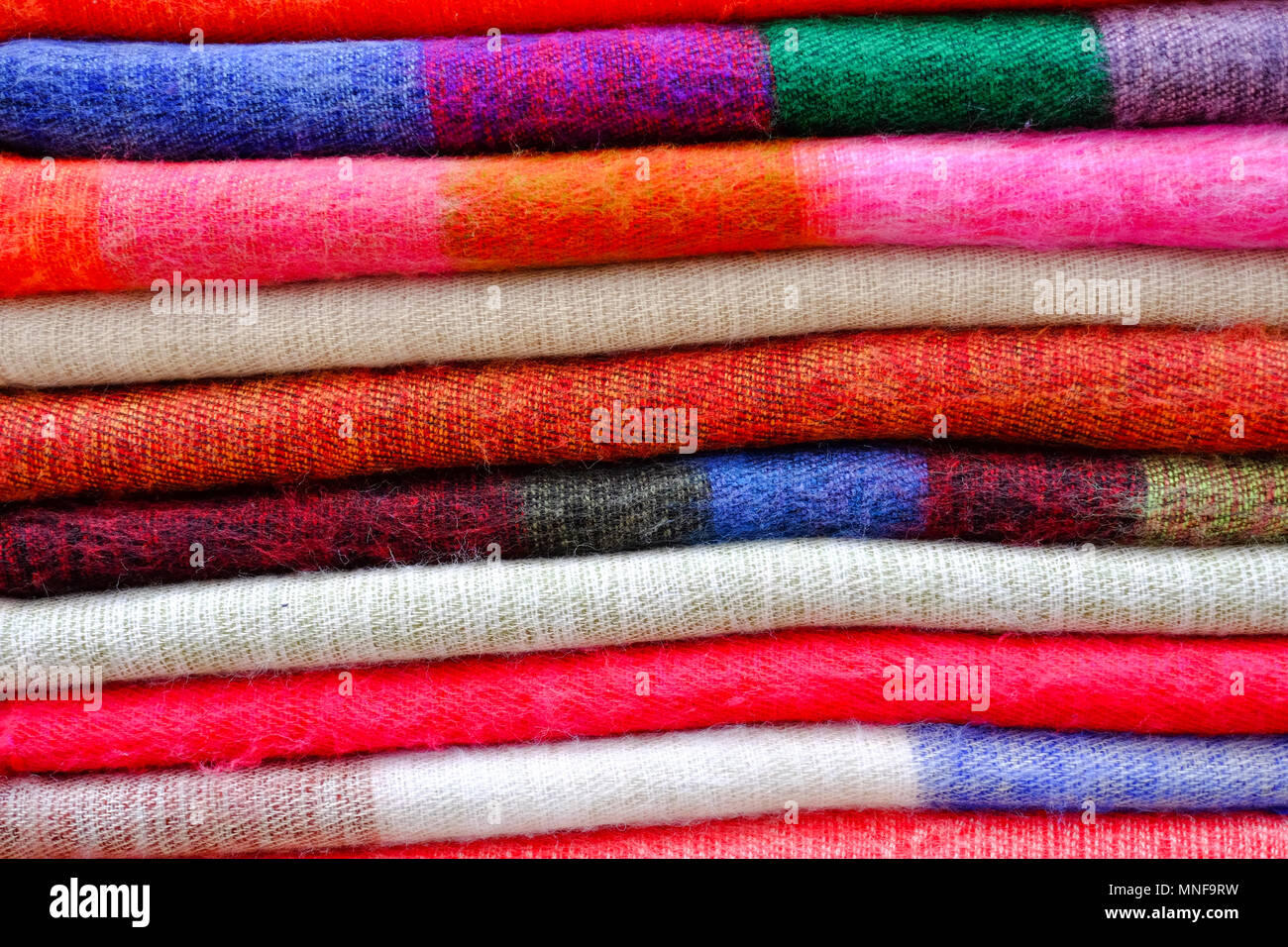 Laine à tricoter écharpe colorée tissu pliés et empilés dans une rangée pour  l'arrière plan Photo Stock - Alamy