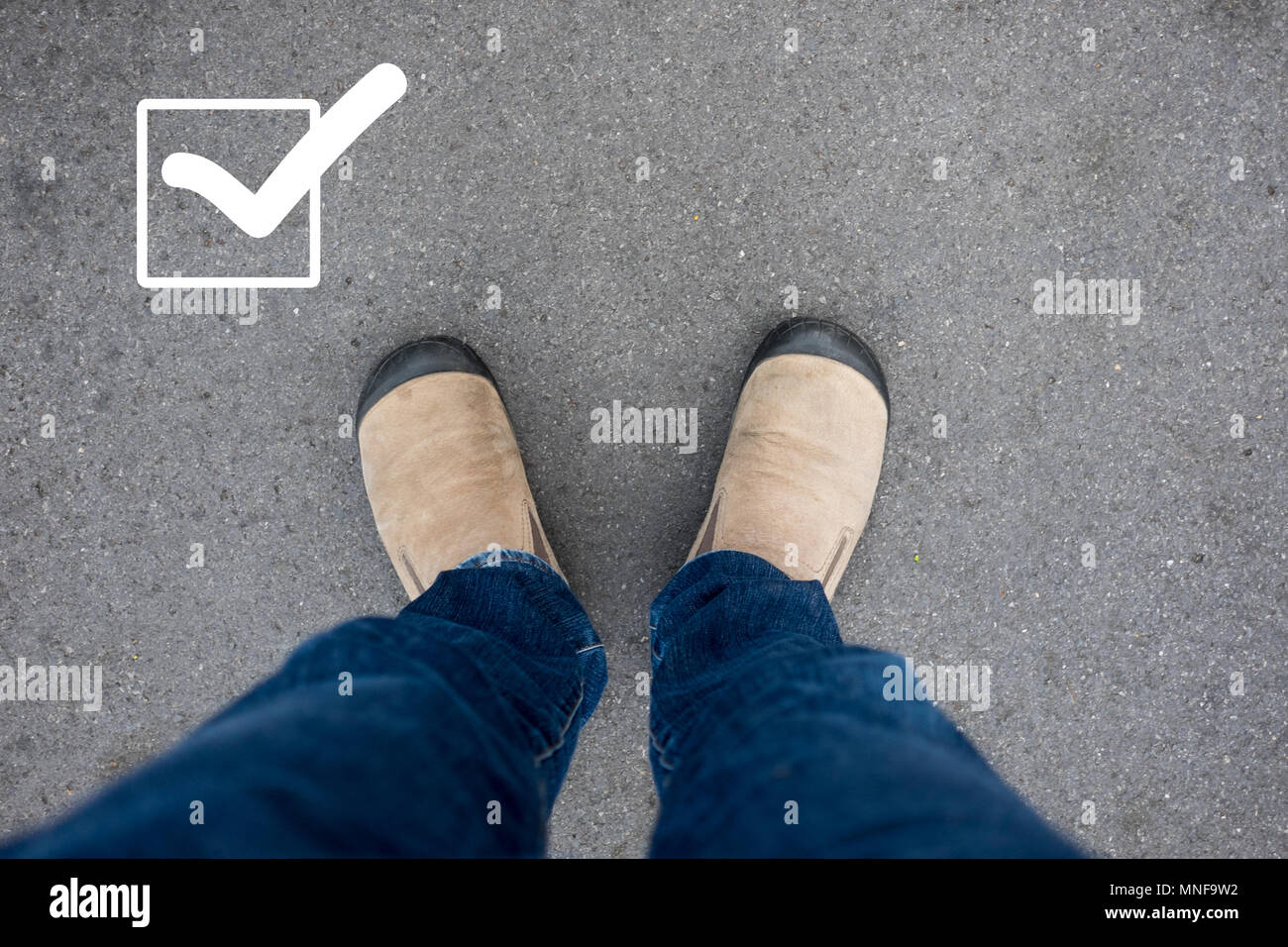 Chaussures en daim marron debout sur un sol en béton d'asphalte avec une case marquée sur le haut à gauche. Banque D'Images