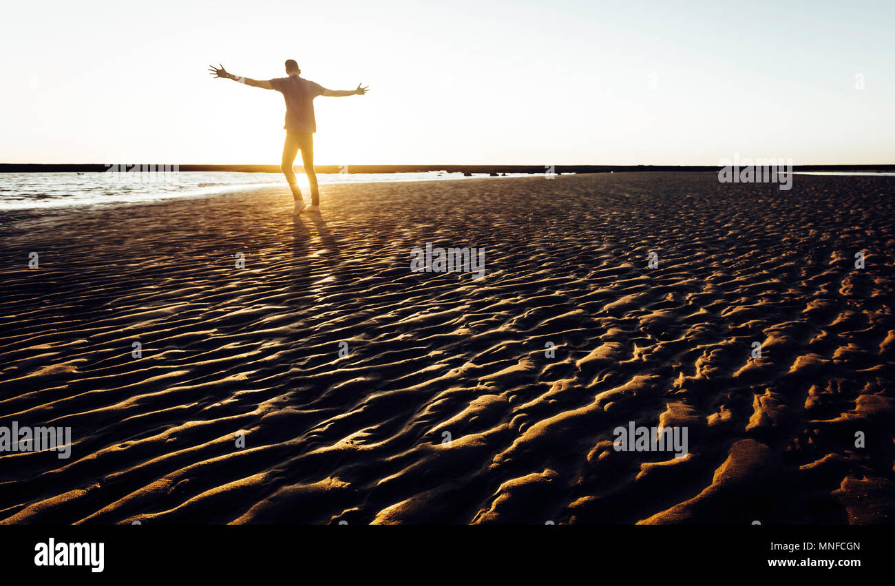 Silhouette de jeune homme debout au coucher du soleil sur la plage de Sanlucar de Barrameda Banque D'Images