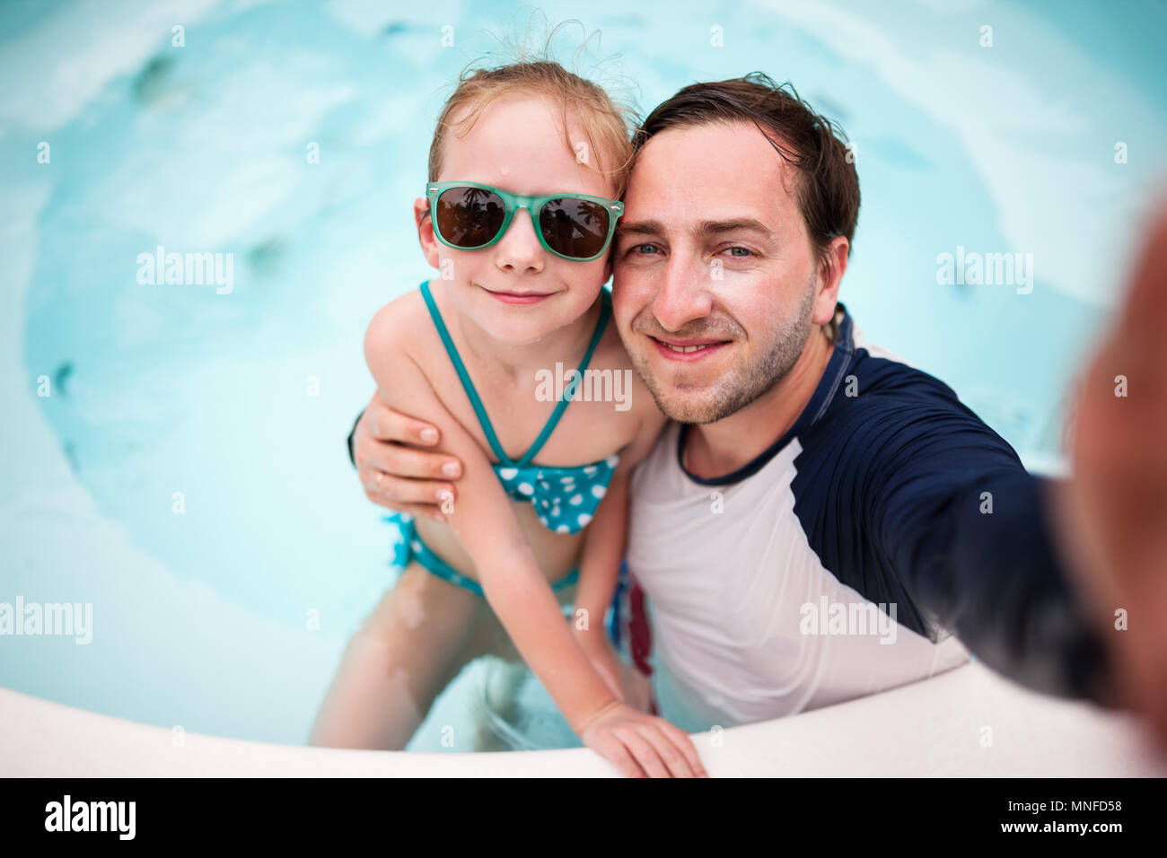 Père de famille heureuse et son adorable petite fille à l'extérieur piscine faire selfies Banque D'Images