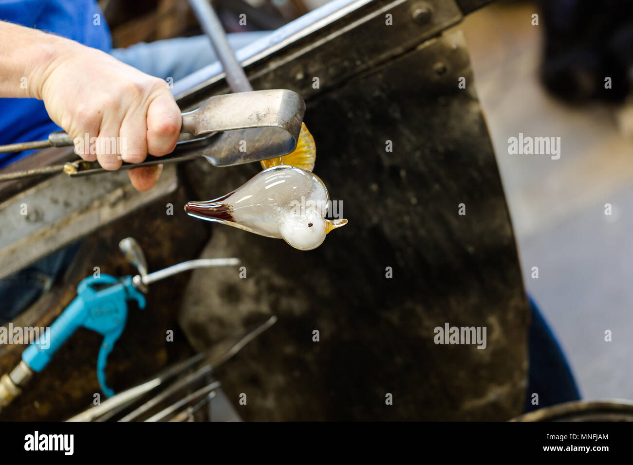 Artiste de verre dans un verre fabrication travaille sur seagull sculpture faite de verre chaud. Se concentrer sur les mains et la figure seagull. Close up shot Banque D'Images